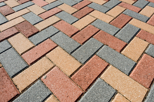 Rubber pavers installed in such a way to closely resemble bricks.  The pavers are black, red, tan, brown and have white speckles and imperfections on the surface just like bricks.