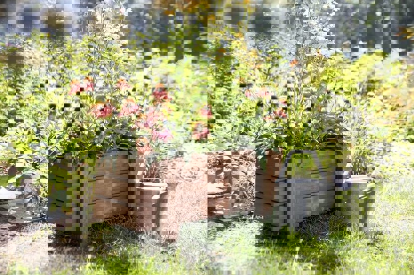 Flowers in a handmade planter box with a gardening water can next to the box.