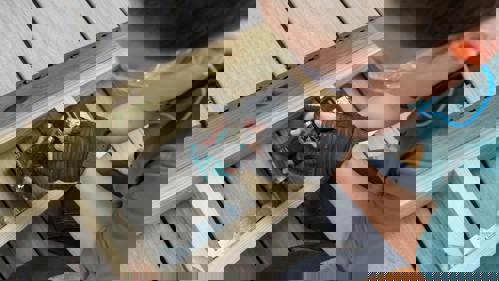 Person with a electric drill in their hand screwing in a bracket on box stairs